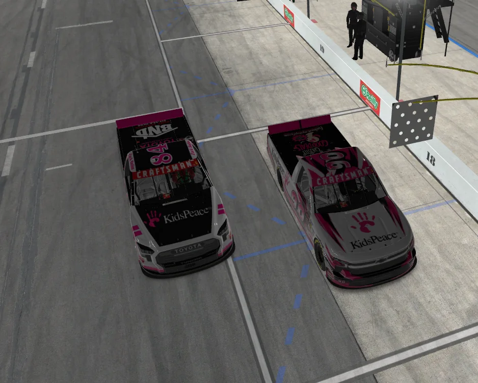 Two KidsPeace themed virtual race trucks together on pit road